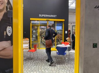 Man sieht den Gilgen Stand an der BAU Messe mit den gelben Ausstellungstüren und dem CEO der durch läuft.