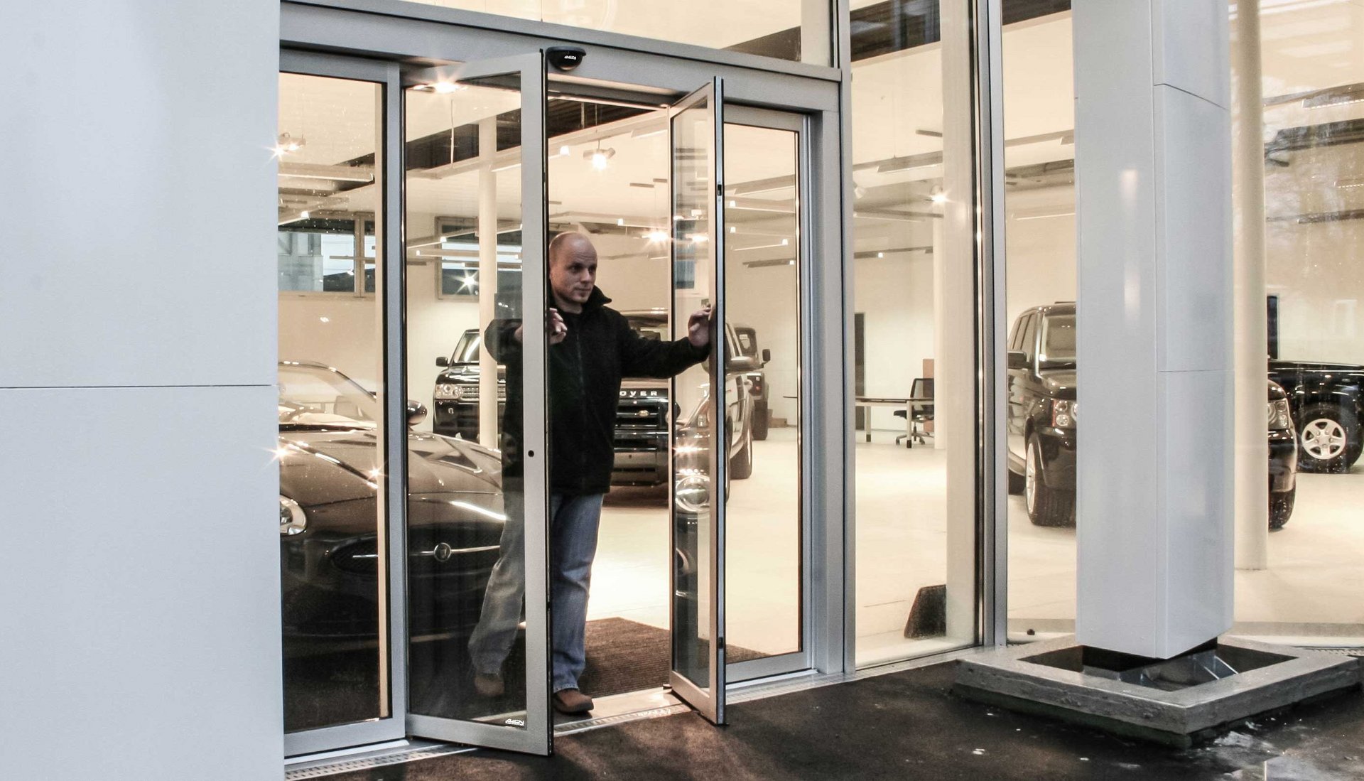 Flüchtende Person aus dem Autohaus mit einer Fluchtweg-Schiebetür bei offenen Türflügeln